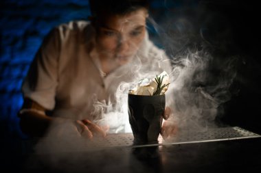 Yakın plan siyah seramik eski moda cam, buzla süslenmiş, dumanlı tezgahın üzerinde duruyor..