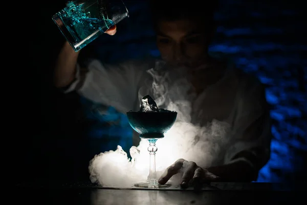 Camarero vierte cóctel azul de la taza de mezcla en vidrio en el bar ahumado oscuro . — Foto de Stock