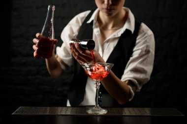 Profesyonel barmen ustaca barın tezgahında bardaklara içki doldurur..