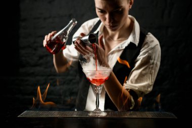 Profesyonel barmen, barın üzerinde duran bardağa ustalıkla içki koyar.