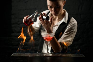 Profesyonel barmen bardağın içine içki koyar.