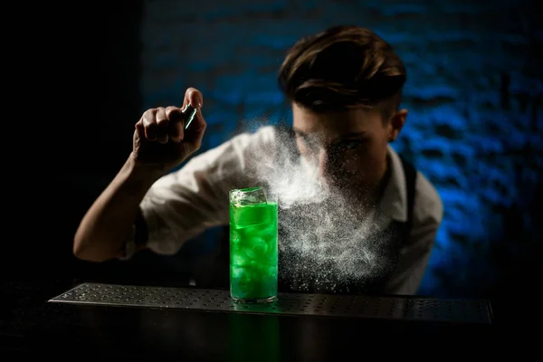 Bartender sprinkles on glass with bright green cocktail and look at it. — Stock Photo, Image