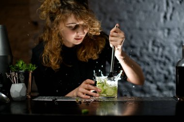 female bartender actively mixing cocktail using madler. clipart