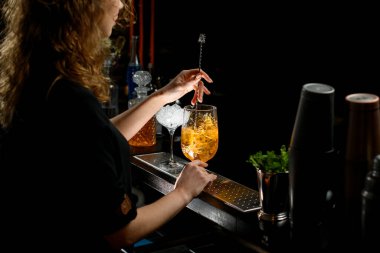 Genç barmen bar kaşığıyla alkollü kokteyli karıştırdı..