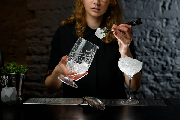 Barman fêmea detém vidro e colocar pedaço de gelo nele . — Fotografia de Stock