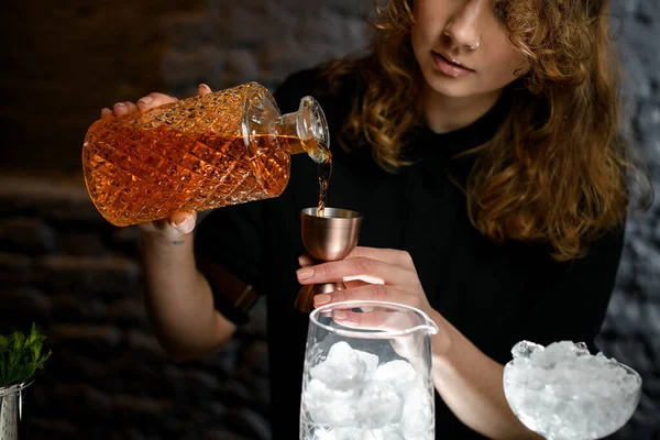 Jovem bartender derrama bebida de garrafa em jigger — Fotografia de Stock