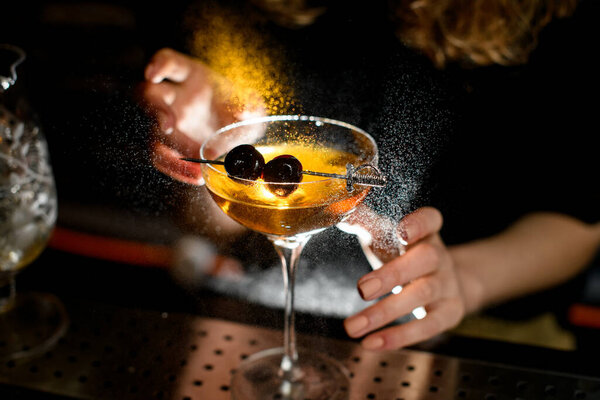Close-up glass with ready-made cocktail accurate decorated berries and sprinkles by bartender