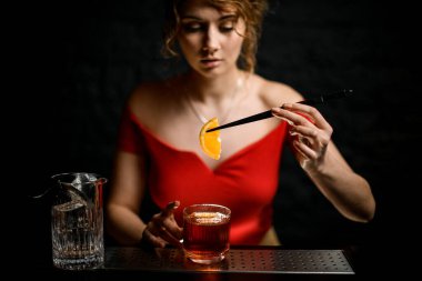 Genç ve güzel bir kız bardağı limon dilimleriyle süslüyor..