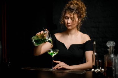 Siyah bluzlu güzel kadın bardaklara alkollü içkiler döker..