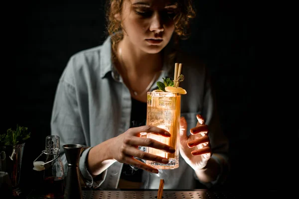 young woman at bar holds beautiful cocktail with ice
