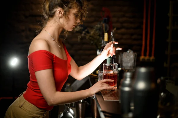 Sexy vrouw aan bar gemengde cocktail door lange bar lepel. — Stockfoto