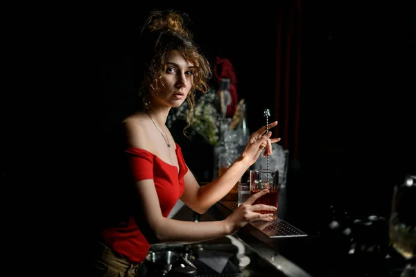 Vacker ung kvinna bartender blandad cocktail med lång bar sked. — Stockfoto