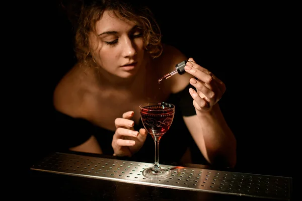 Vacker ung kvinna i baren lägga ingrediens att dricka med dropper — Stockfoto