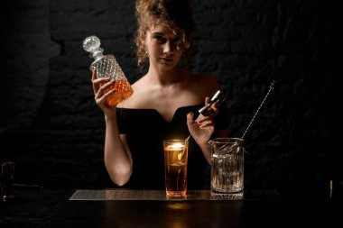 Aydınlatılmış cam, dikenli içecekle süslenmiş bardaklar ve karıştırma bardakları tezgahın üzerinde duruyor.