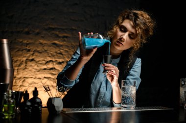 Genç bayan barmen barmen şişeden jigger 'a kadar içiyor.