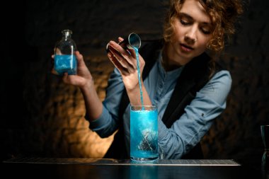 Bardaki genç kadın nazikçe jiggerdan bardağa su döker.