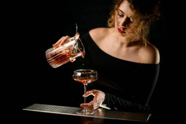 Barmen kız bardağa karıştırdıktan sonra soğuk kokteyli dolduruyor.