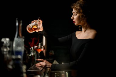 Karanlık bardaki seksi kadın barmen kadehini yavaşça şarap bardağına dolduruyor..