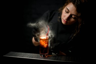Genç barmen spreyi. Kokteyl bardağında. Bitkilerle süslenmiş..