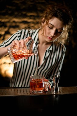 Barmen kadın bardakları karıştırırken dikkatli bir şekilde hazır soğuk kokteyl koyuyor.