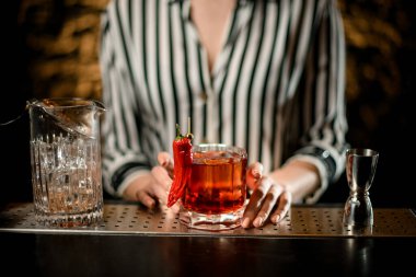 Barın üzerinde kırmızı biberlikle süslenmiş eski moda bardaklar var..