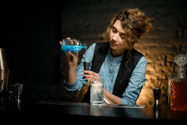 Giovane donna barista versa attentamente bere dalla bottiglia in jigger e guardalo . — Foto Stock
