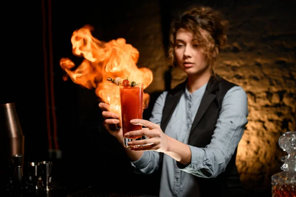 Барменша, держащая стекло с коктейльной крошкой на нем и разжигающая огонь . — стоковое фото