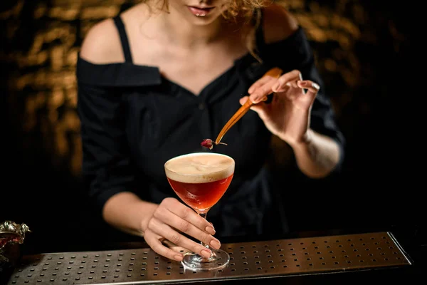 Close-up meisje aan bar versiert door bloemglas met rood zure cocktail — Stockfoto