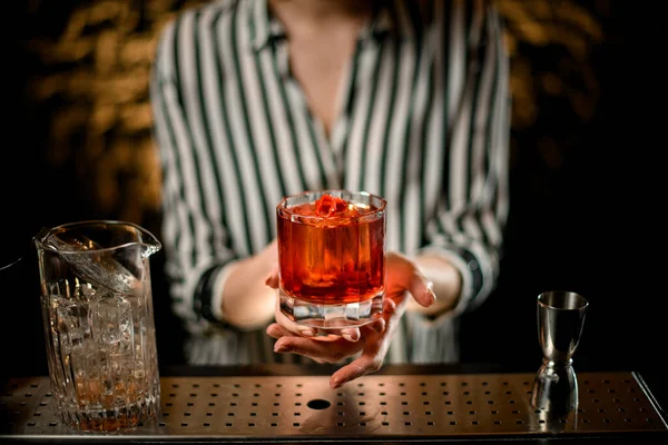 Close-up old-fashioned glass with cocktail decorated with red pepper in woman hands at bar — Stock Photo, Image