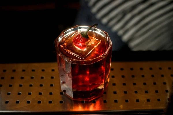 Szklanka z bliska z napojem i kawałkiem lodu stojącym przy barze — Zdjęcie stockowe