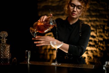 Profesyonel bayan barmen bardakları bardağa karıştırırken ustaca kokteyl doldurur..