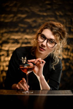 Güzel kadın barmen bardağı beyaz çiçekle süslüyor..