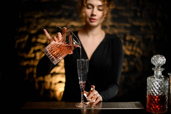 Bartender girl pours ready-made cold cocktail from mixing cup into glass — Stock Photo, Image