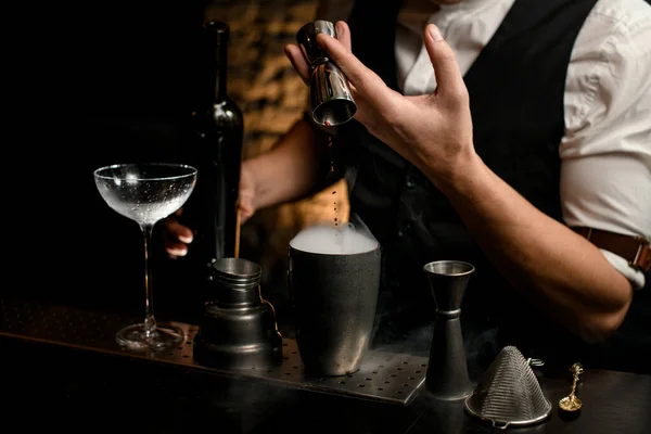 Close-up männliche Barkeeper gießt Getränk aus Metall Jigger in rauchigen Stahlbecher Shaker — Stockfoto