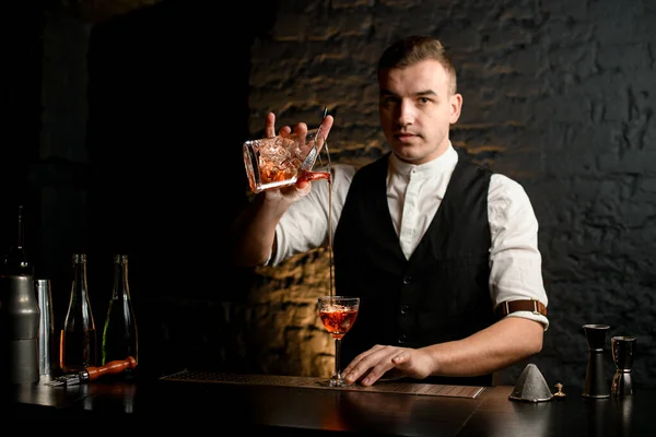 Jovem barman no bar derrama coquetel em vidro — Fotografia de Stock