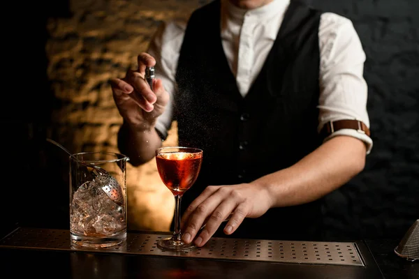 Närbild. Bartender strör försiktigt på glas med cocktail på bardisken. — Stockfoto