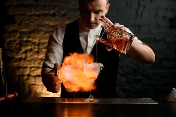 Close-up. Barman cuidadosamente derrama coquetel para polvilhar de vidro para ele e fazer fogo . — Fotografia de Stock