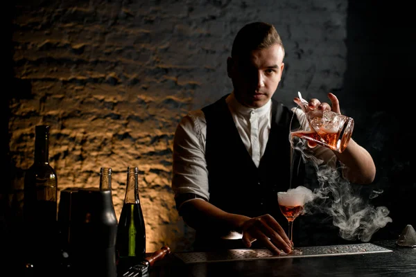 Крупный план. Профессиональный бармен аккуратно наливает коктейль в дымчатое стекло — стоковое фото
