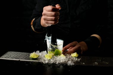 Yakın plan. Barmen Madler 'i tutuyor ve Caipirinha kokteyline limon dilimleri sıkıyor.