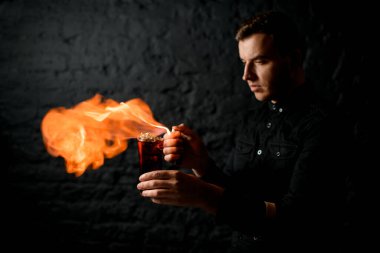 Profesyonel barmen bardağını kokteyl ile tutar ve onu ateşe verir..