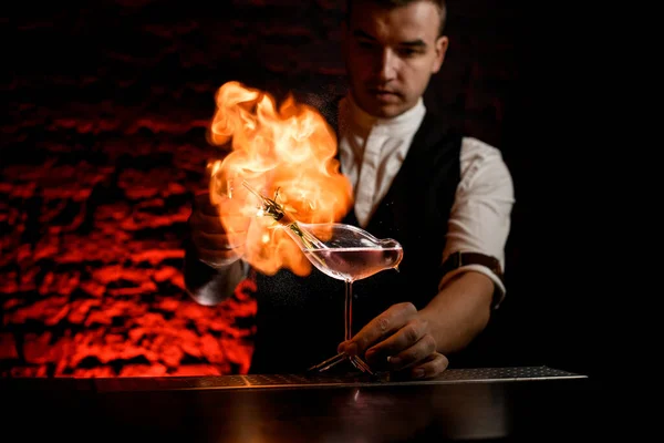 Maschio barista spruzza e fa fuoco fiamma sopra vaso di vetro a forma di uccello — Foto Stock