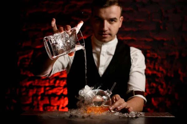 Il barista maschile versa professionalmente una bevanda fredda in una fiaschetta fumosa — Foto Stock