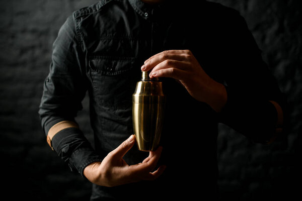 Close-up of steel shaker in barmans hands.