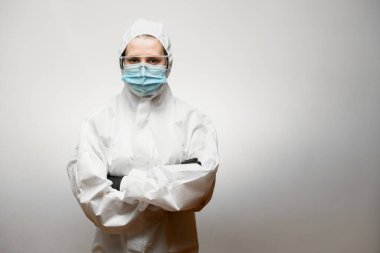 Kolları beyaz arka planda çaprazlanmış koruyucu ekipman kullanan bilim adamı.