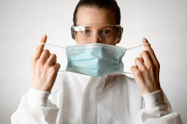 Femme en costume de protection blanc et lunettes met sur masque médical — Photo