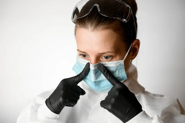 Портрет молодой женщины, которая регулирует медицинскую маску пальцами — стоковое фото