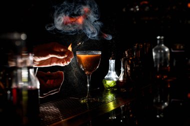 Barmenlerin elleri narenciye ile alkollü kokteyl serpiştirir.