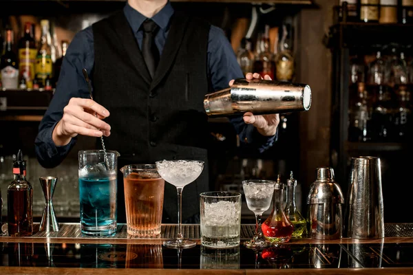 Bartender profissional detém agitador de aço e mistura coquetel — Fotografia de Stock