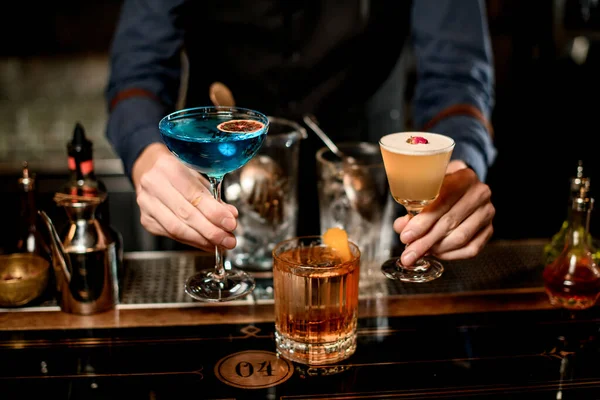 Nahaufnahme. Männlicher Barkeeper präsentiert drei verschiedene Cocktails — Stockfoto