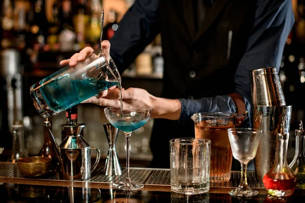 Barmann gießt sanft blauen Cocktail aus Mixbecher ins Glas — Stockfoto